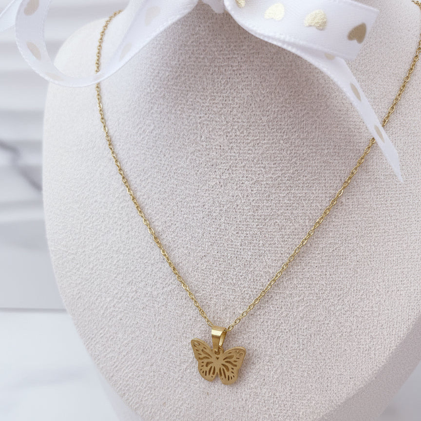 Collar de mariposa dorada de acero inoxidable exhibido sobre maniquí blanco.