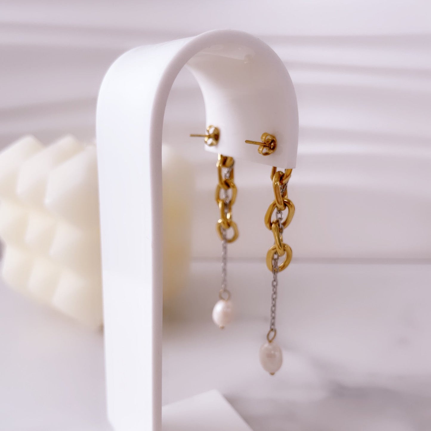 Aretes de perlas Vanytel exhibidos sobre base blanca, joyería elegante.