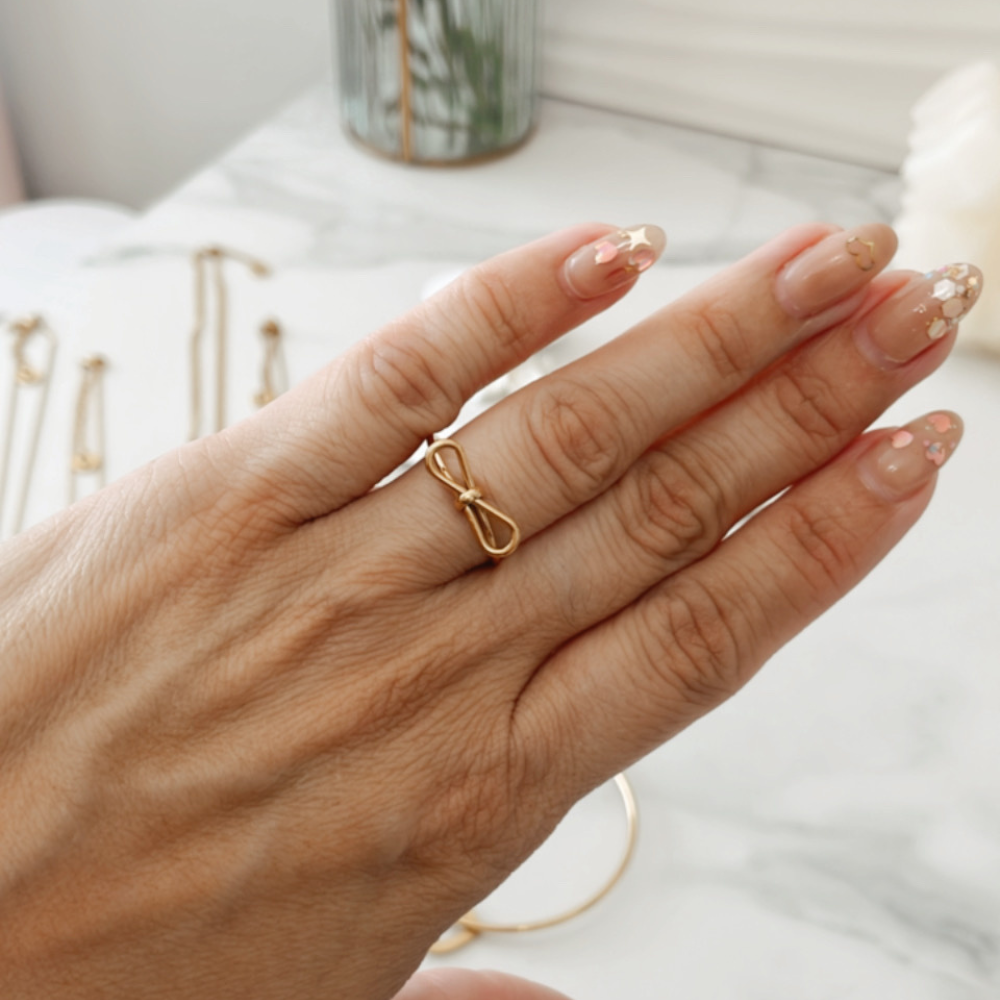 Anillo Alicia Vanytel ajustable en acero inoxidable dorado lucido en la mano, diseño moderno y chic.
