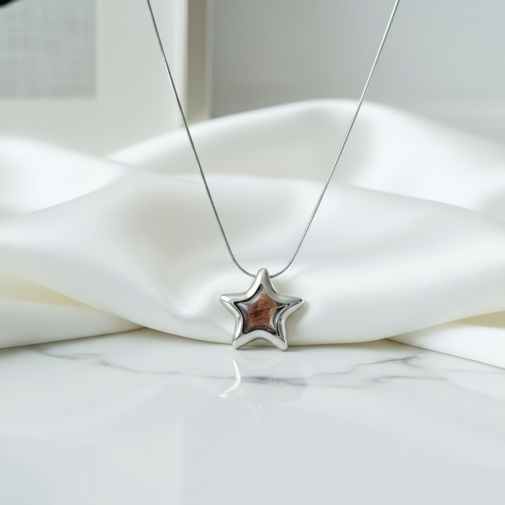 Detalle del collar estrella plateado Vanytel sobre busto decorativo, estilo minimalista.
