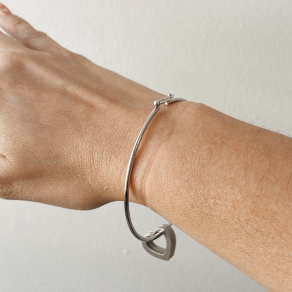 Pulsera Mis Amores Vanytel plateada lucida en la muñeca con dijes de corazón.
